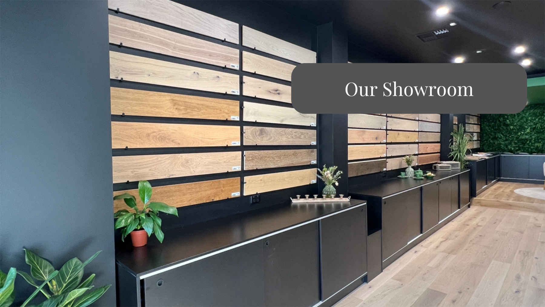 Elite Wooden Floors showroom featuring a display wall of various wooden flooring samples, with a modern interior design.